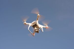 Small FPV drone in flight over open terrain representing autonomous strike drone technology