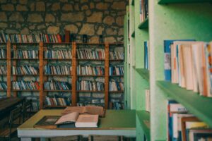 Stack of open books on a wooden library table in warm light