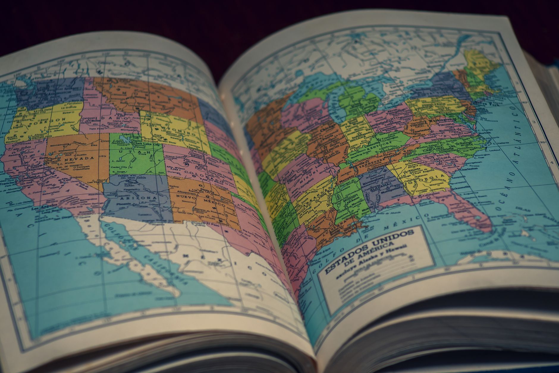 Open book beside a folded paper map on a wooden desk