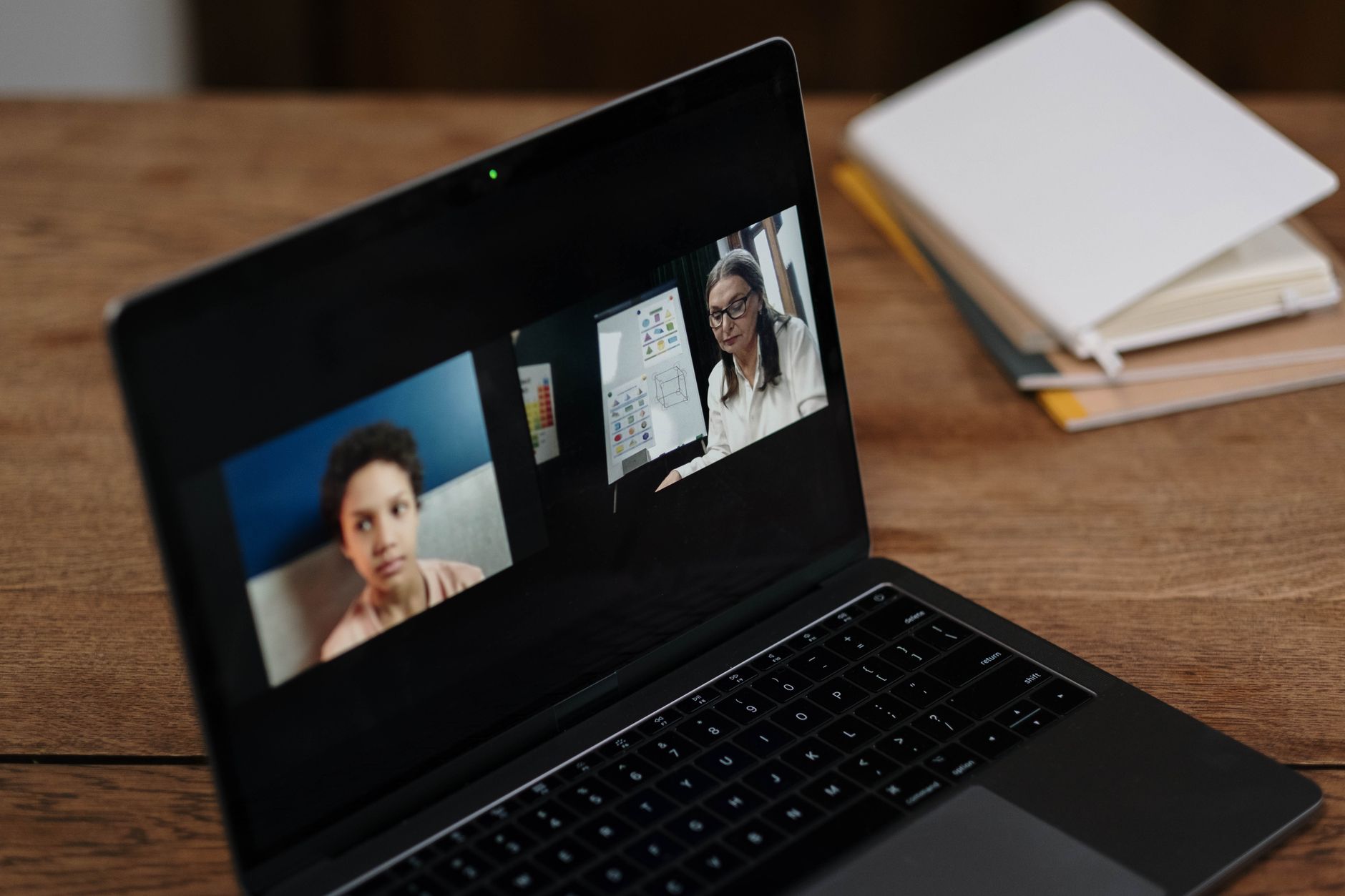 Person attending an online discussion on a laptop, notebook nearby