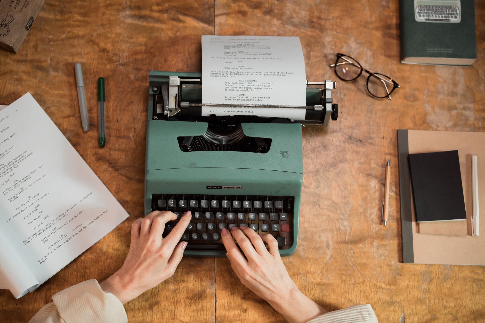 A writer working at a desk with papers and a laptop
