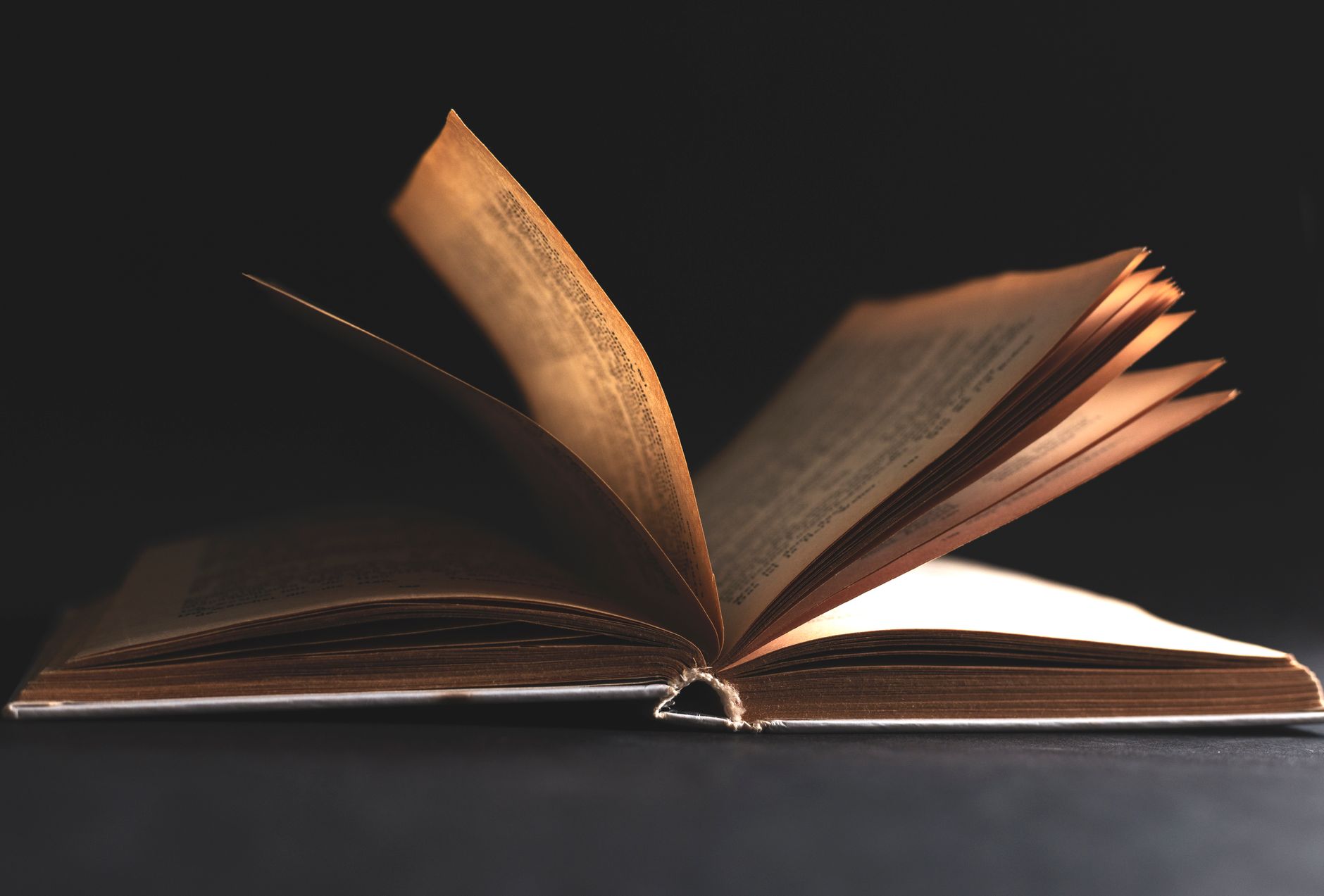 Open notebook with handwritten text next to a foreign language book
