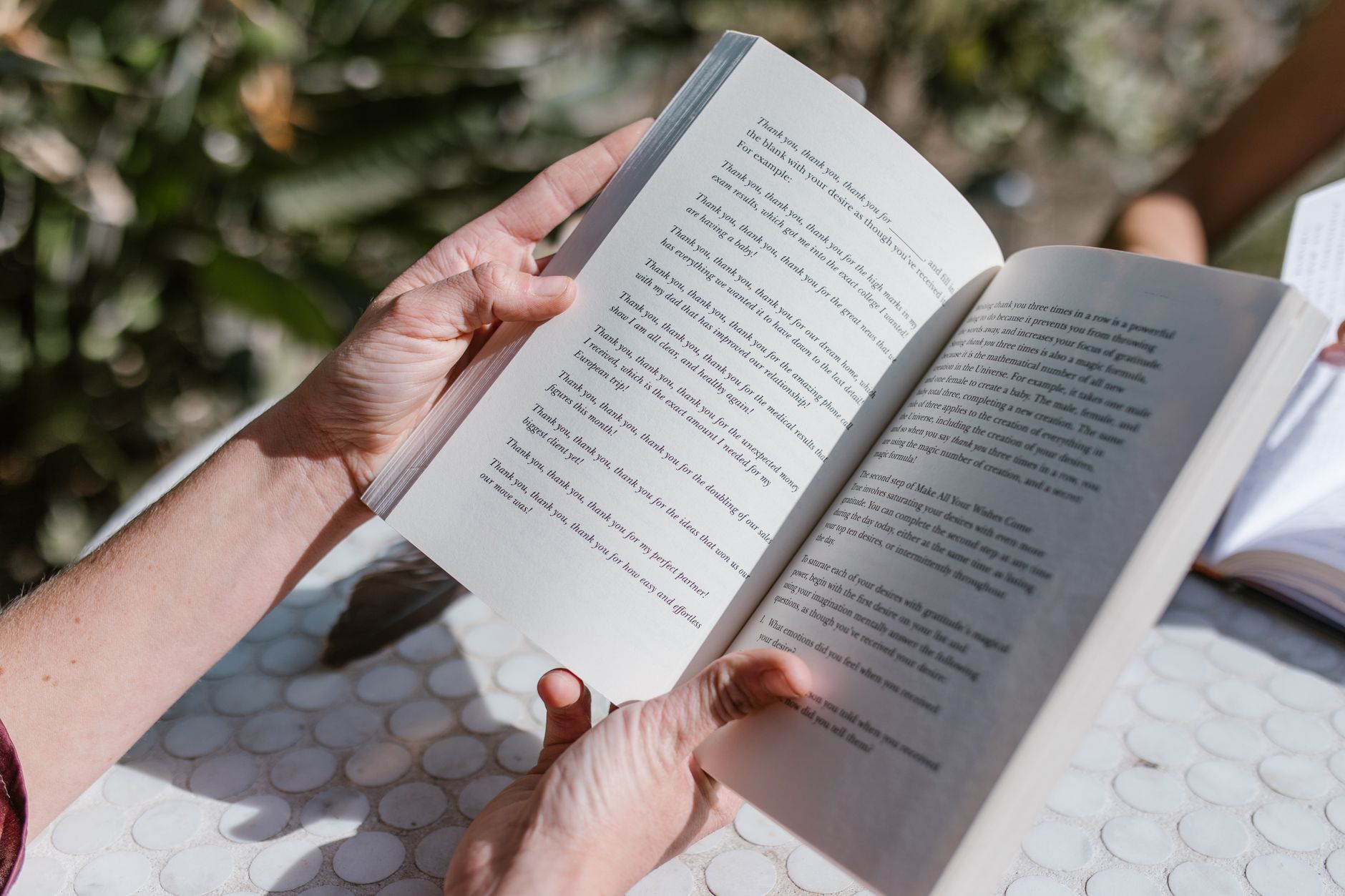 A person reading an open book near a window with natural light