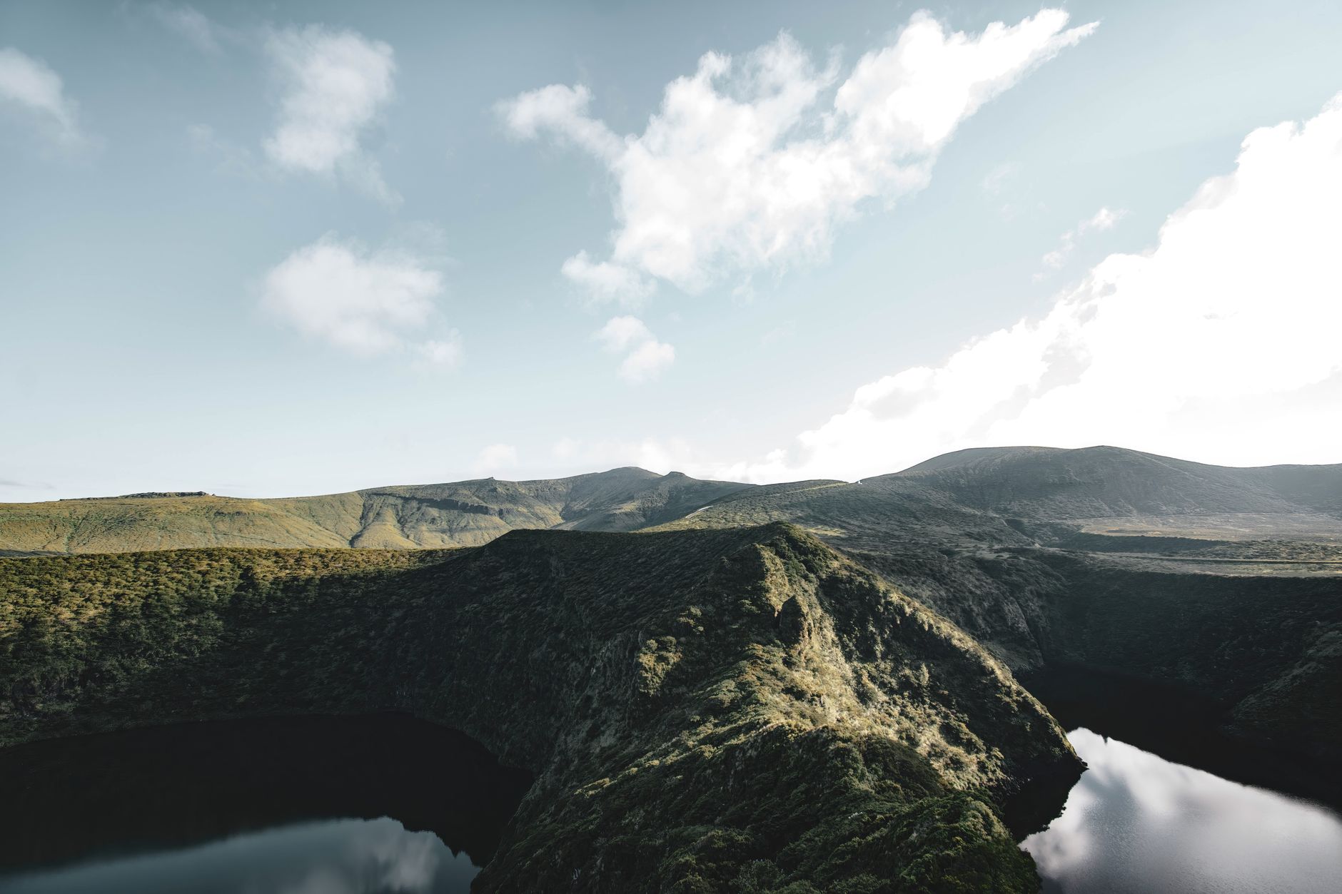 Aerial view of a calm crater lake surrounded by green volcanic terrain