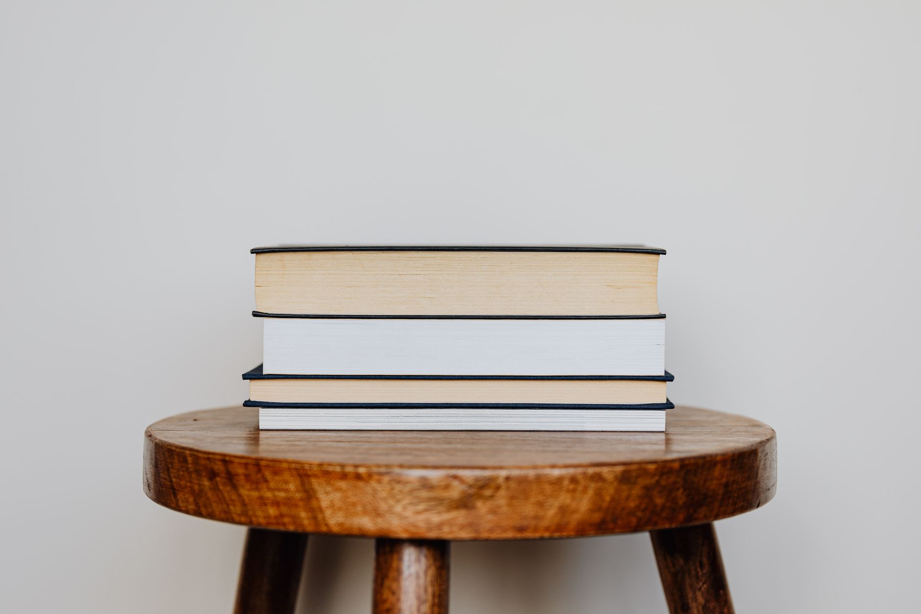 A stack of thick literary novels on a wooden table