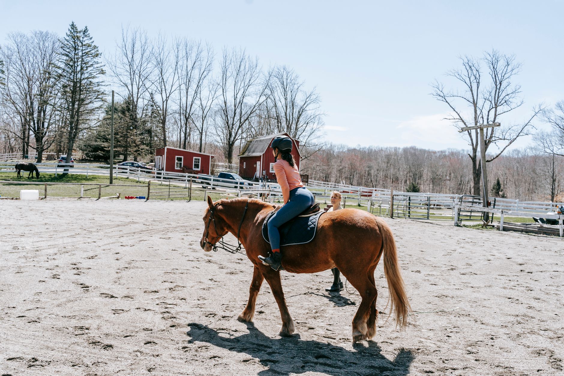 A young girl riding a horse at a slow walk through an open rural landscape