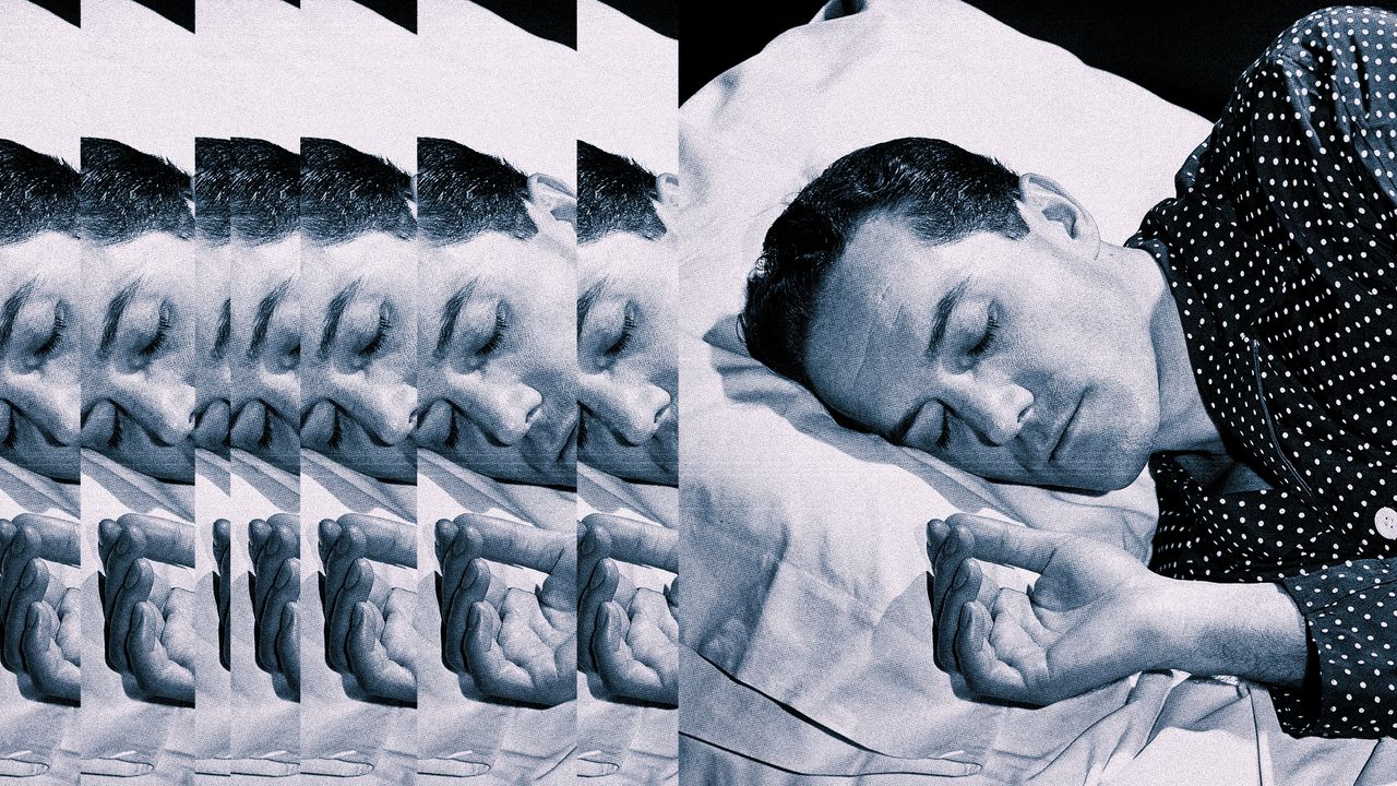 Person sleeping in a dark bedroom with white bedding