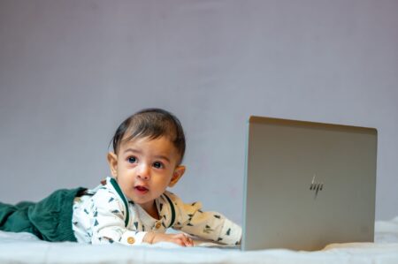 Young child using a laptop while lying on a couch, device resting on abdomen