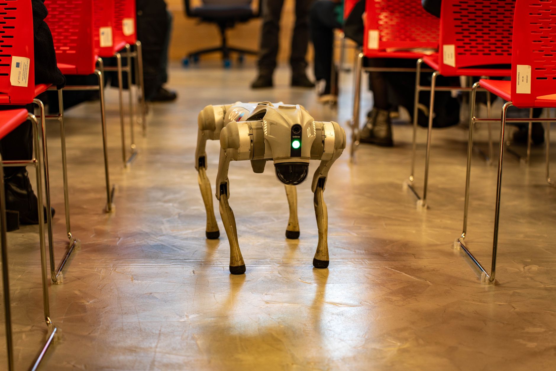 Quadruped robot dog walking on a city sidewalk surrounded by pedestrians
