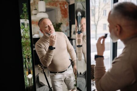 Man examining his face in a bathroom mirror during a morning grooming routine