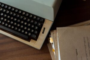 A vintage typewriter sitting on a wooden desk, keys worn from use