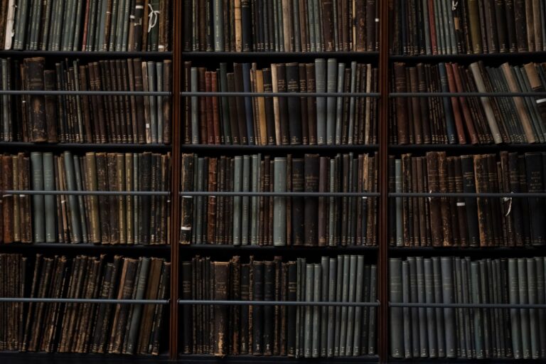 Rows of aged hardcover books on wooden library shelves