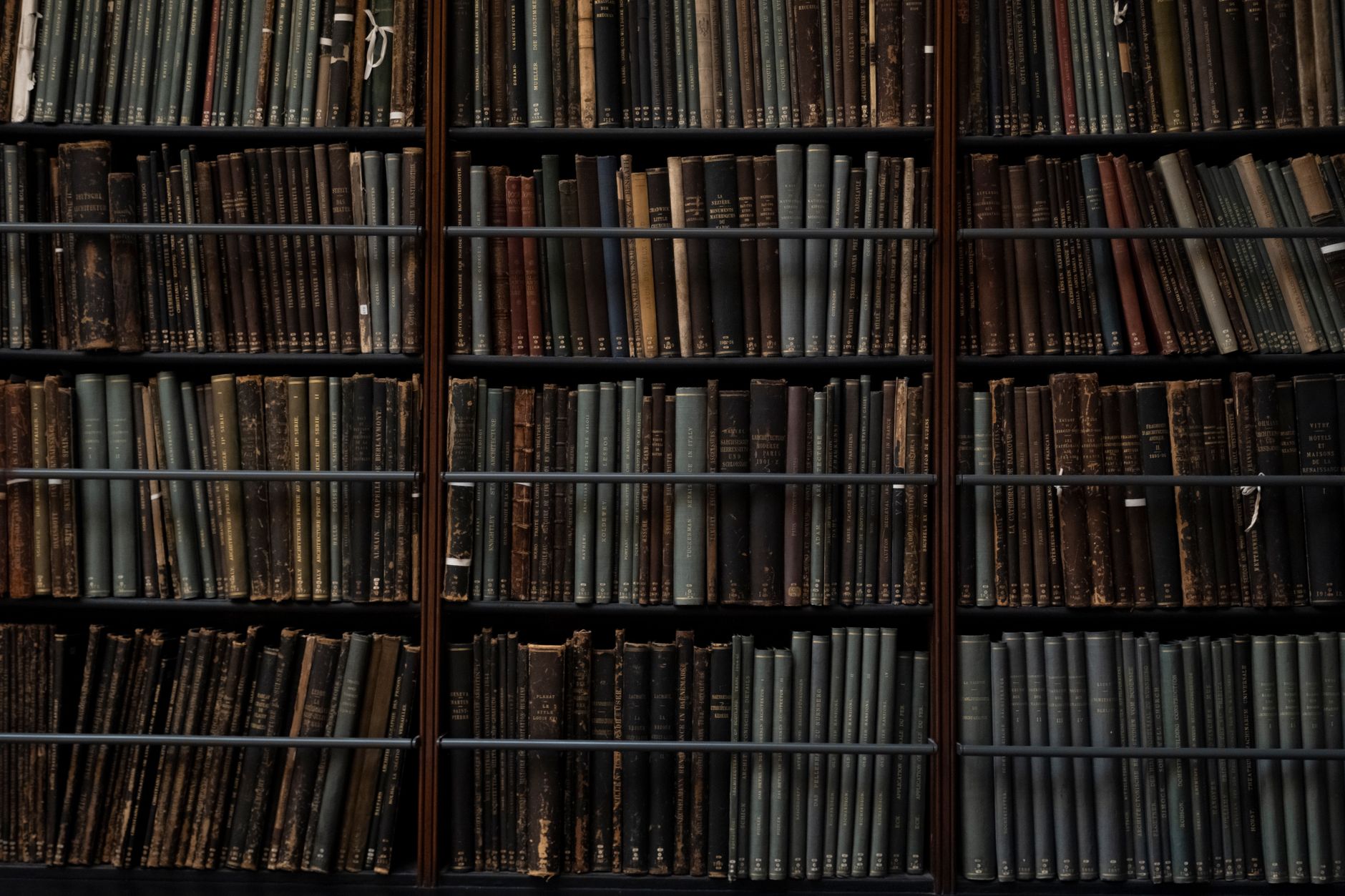Rows of aged hardcover books on wooden library shelves