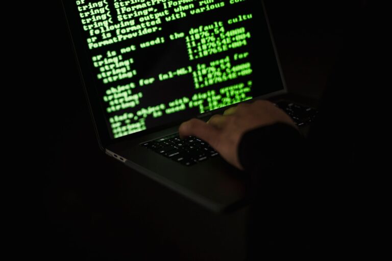 Googles Mandiant Had a Spy Inside TeamPCPs Hacking Inner Circle Person at a computer in a dark room representing underground hacking activity
