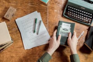 Writing for Readers vs. Writing for Art: A Column Weighs In A writer working at a wooden desk with an open notebook and pen