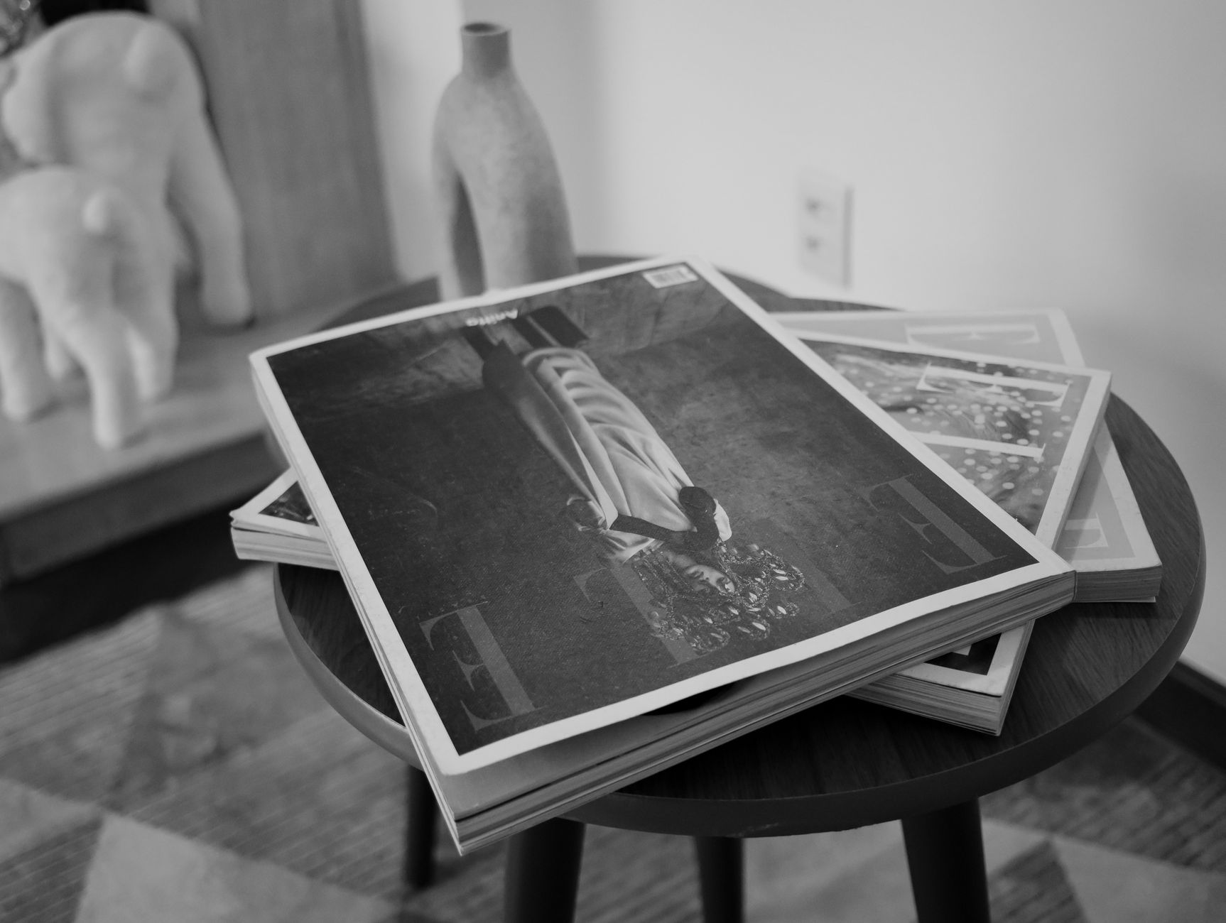 Person reading a print magazine at a desk, letters and papers nearby