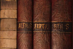 Kiyosaki Owes $1.2 Billion and Other Book World Dispatches Stacked vintage books in a dim library, spines facing outward