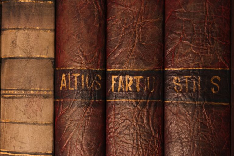 Kiyosaki Owes $1.2 Billion and Other Book World Dispatches Stacked vintage books in a dim library, spines facing outward