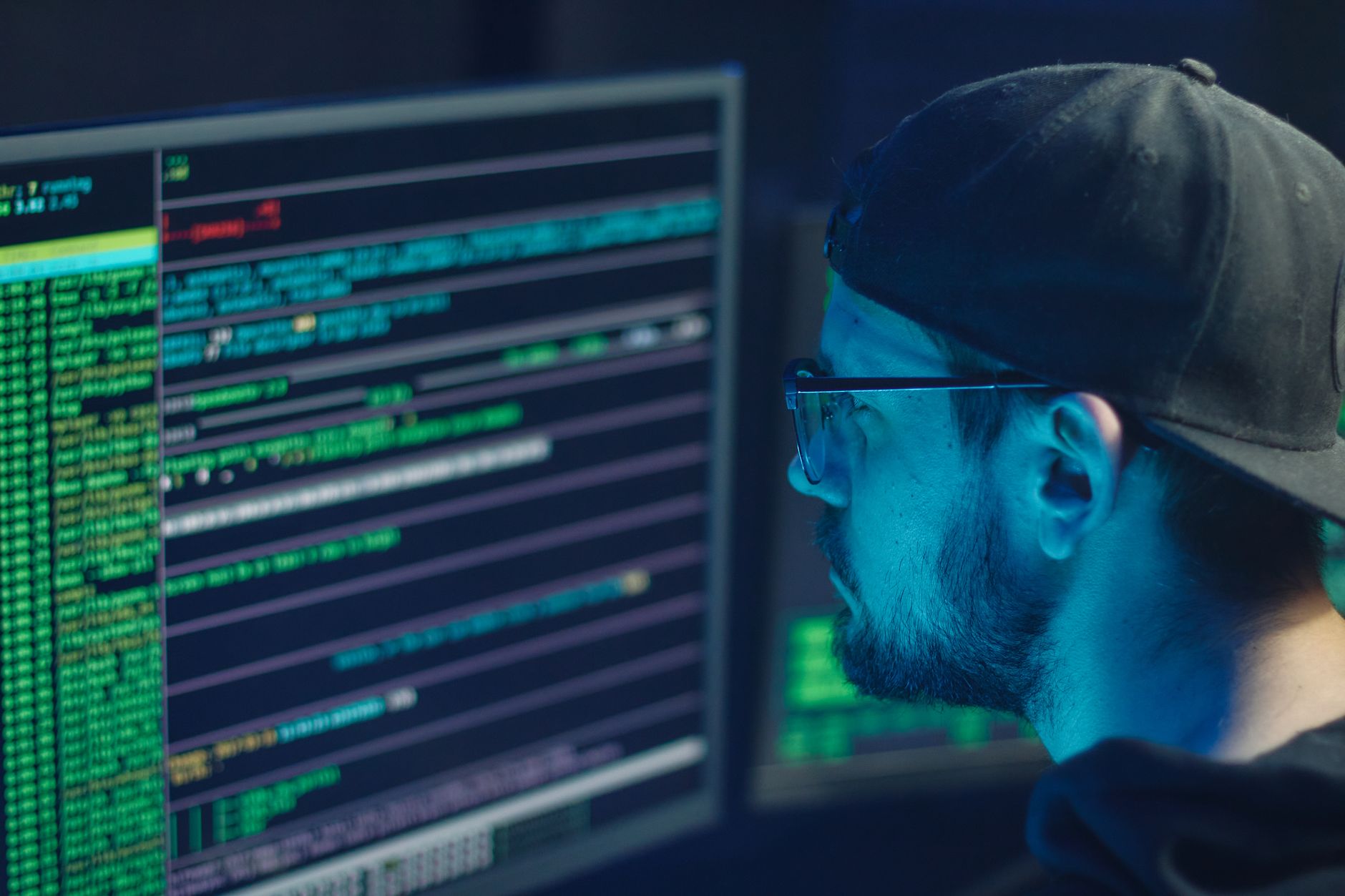 Security analyst reviewing code and threat data on multiple monitors