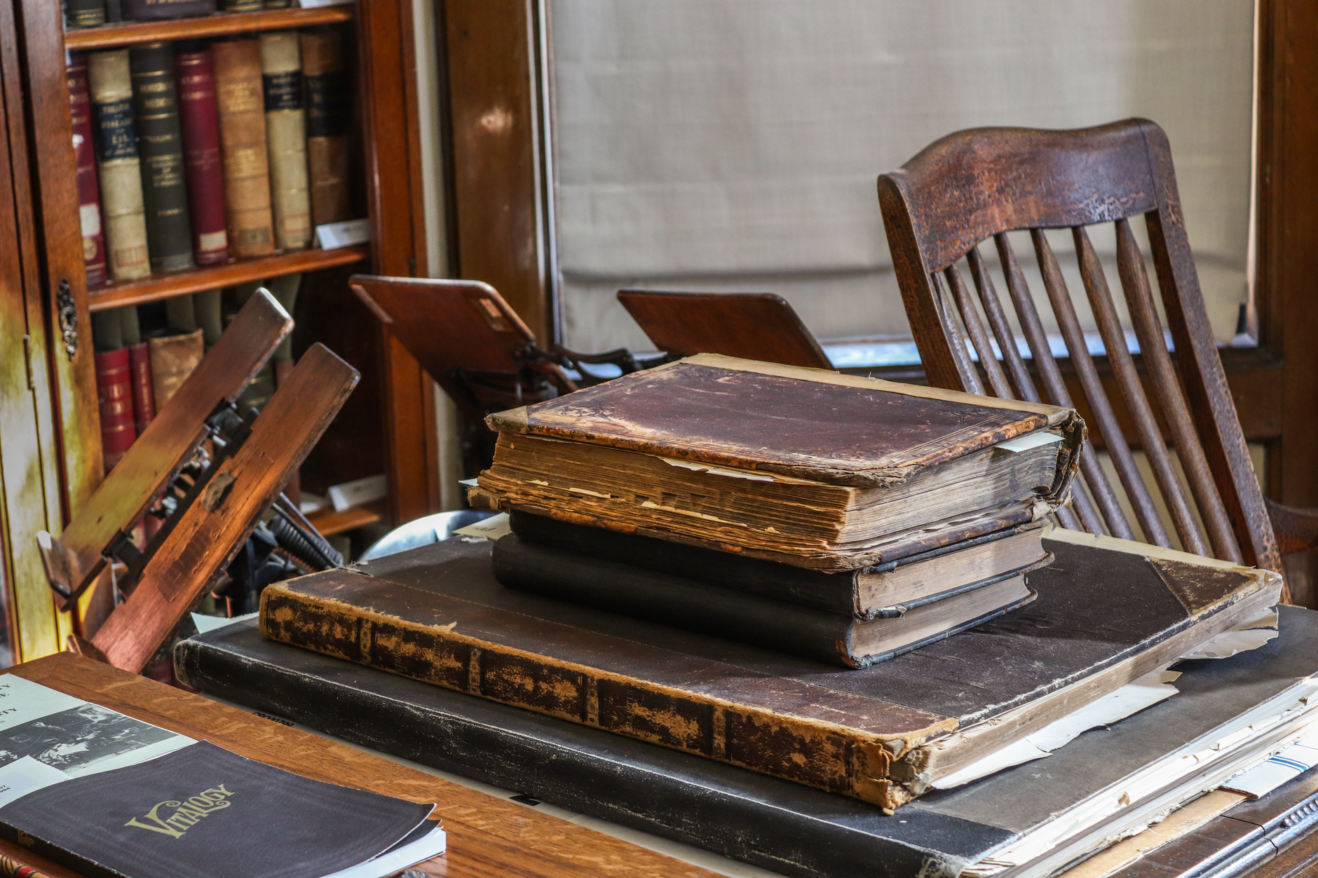 Stack of literary novels on a wooden desk beside a reading lamp