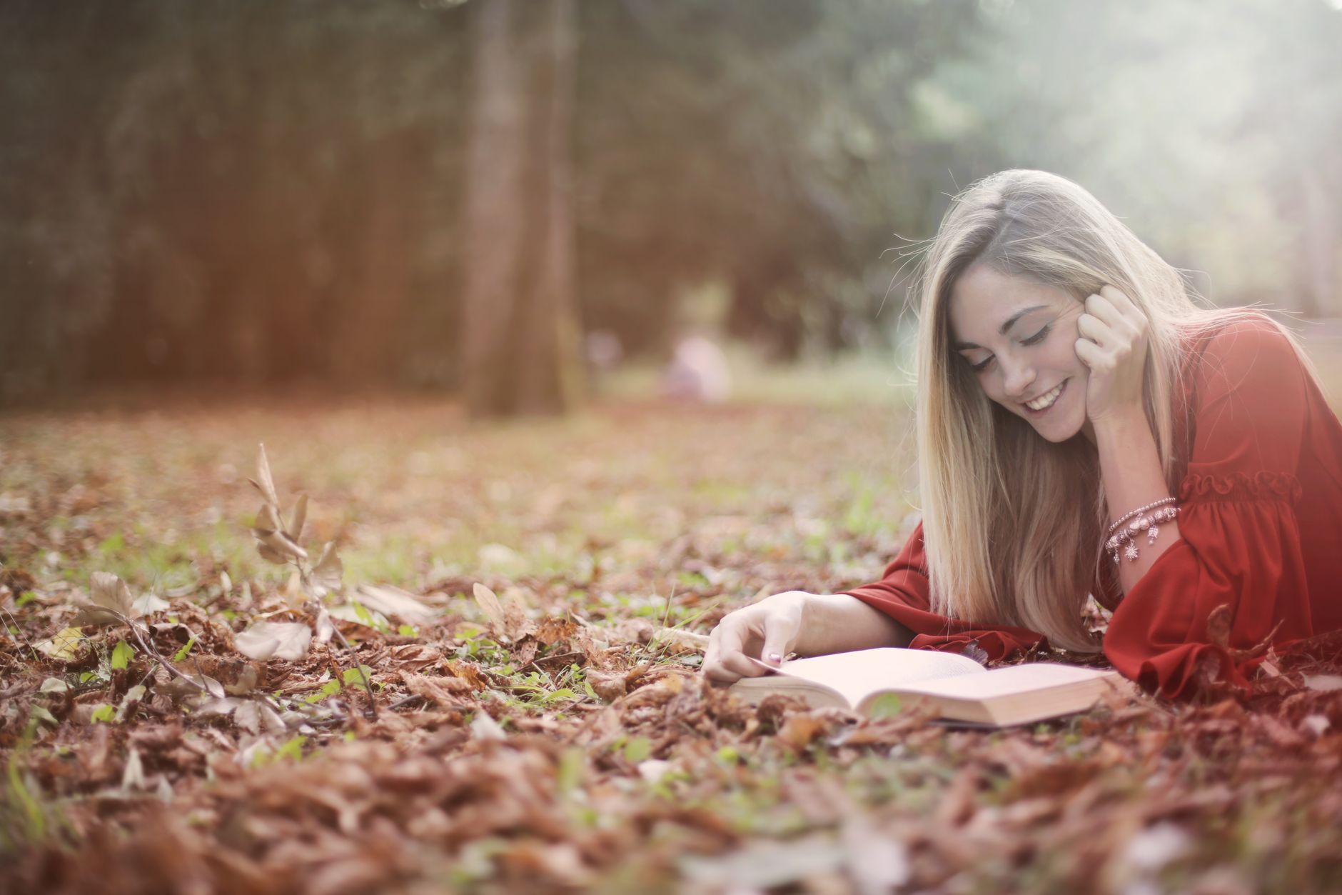 Person reading a book beside a rain-streaked window in autumn light