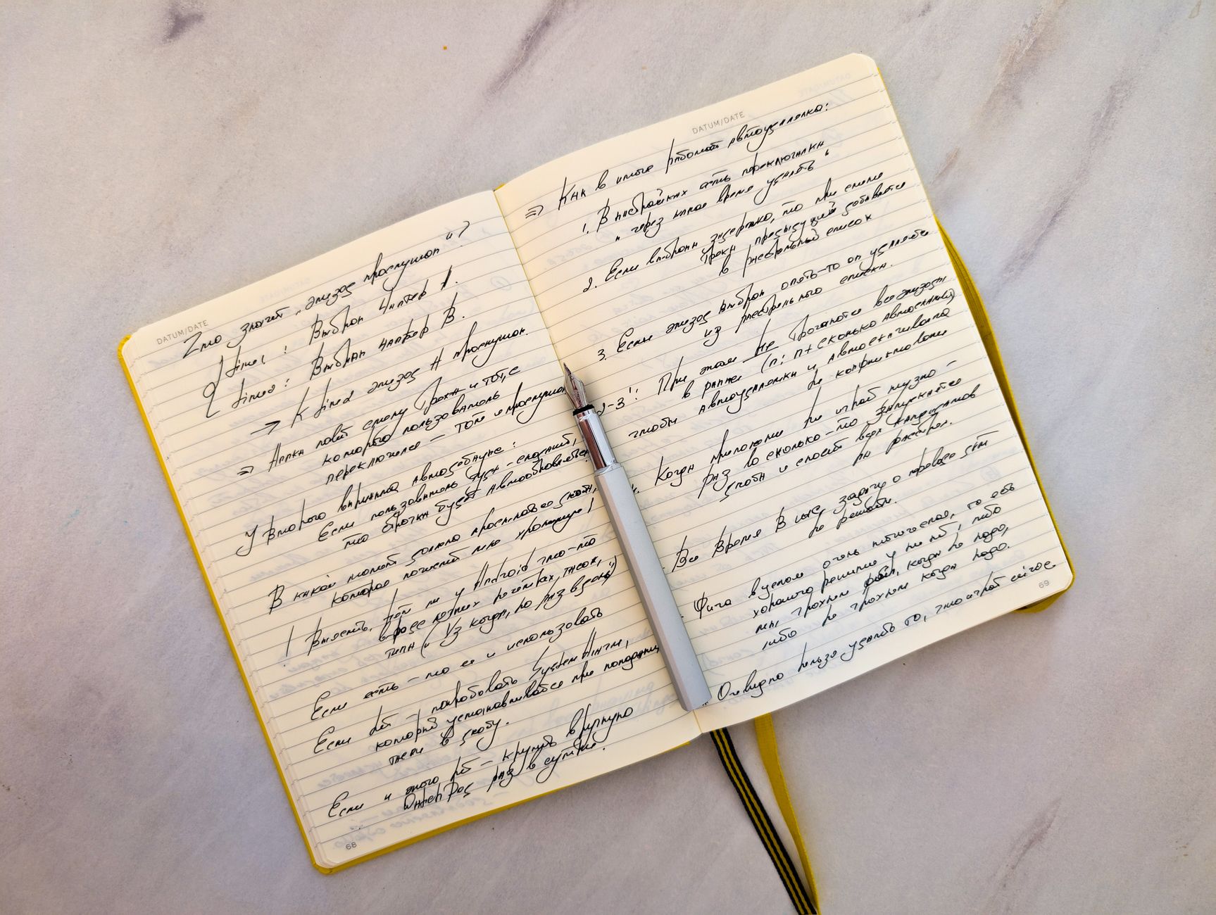 A person writing in an open notebook on a wooden desk