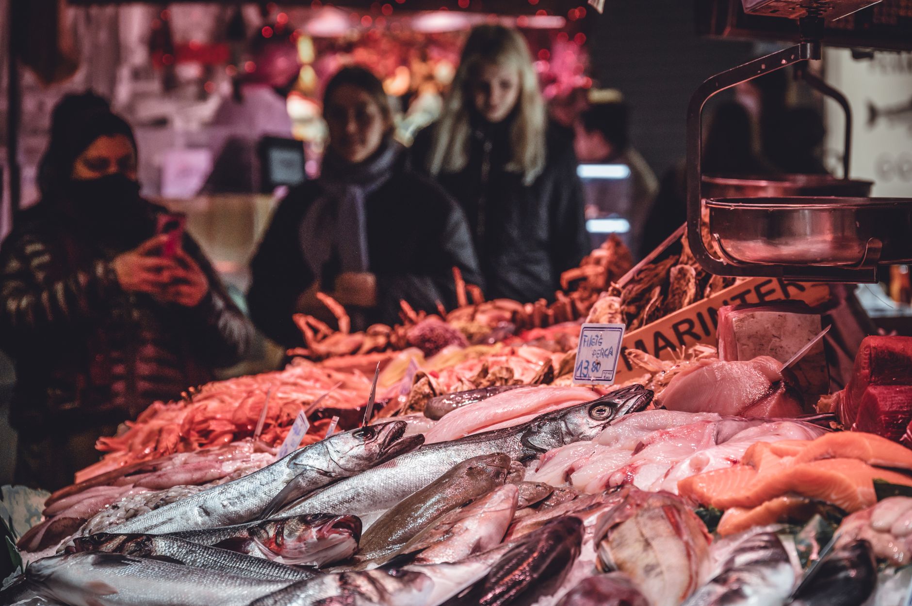 Fresh produce stalls inside a covered Barcelona market with tiled roof detail