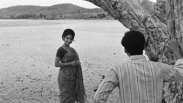 A quiet rural village with dirt paths and trees, evoking the pastoral setting of Satyajit Ray's film