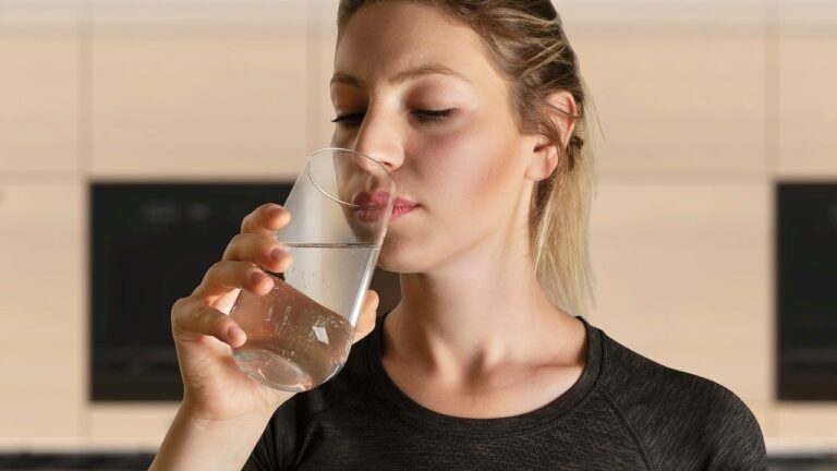 The Girlfriend Care Manual Nobody Asked For A woman sitting at a table reading a handwritten note with a glass of water nearby