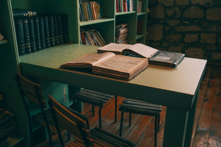 Stack of open books on a wooden library table with warm reading light