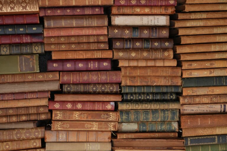 Stacked antique books on a wooden shelf in a dim library