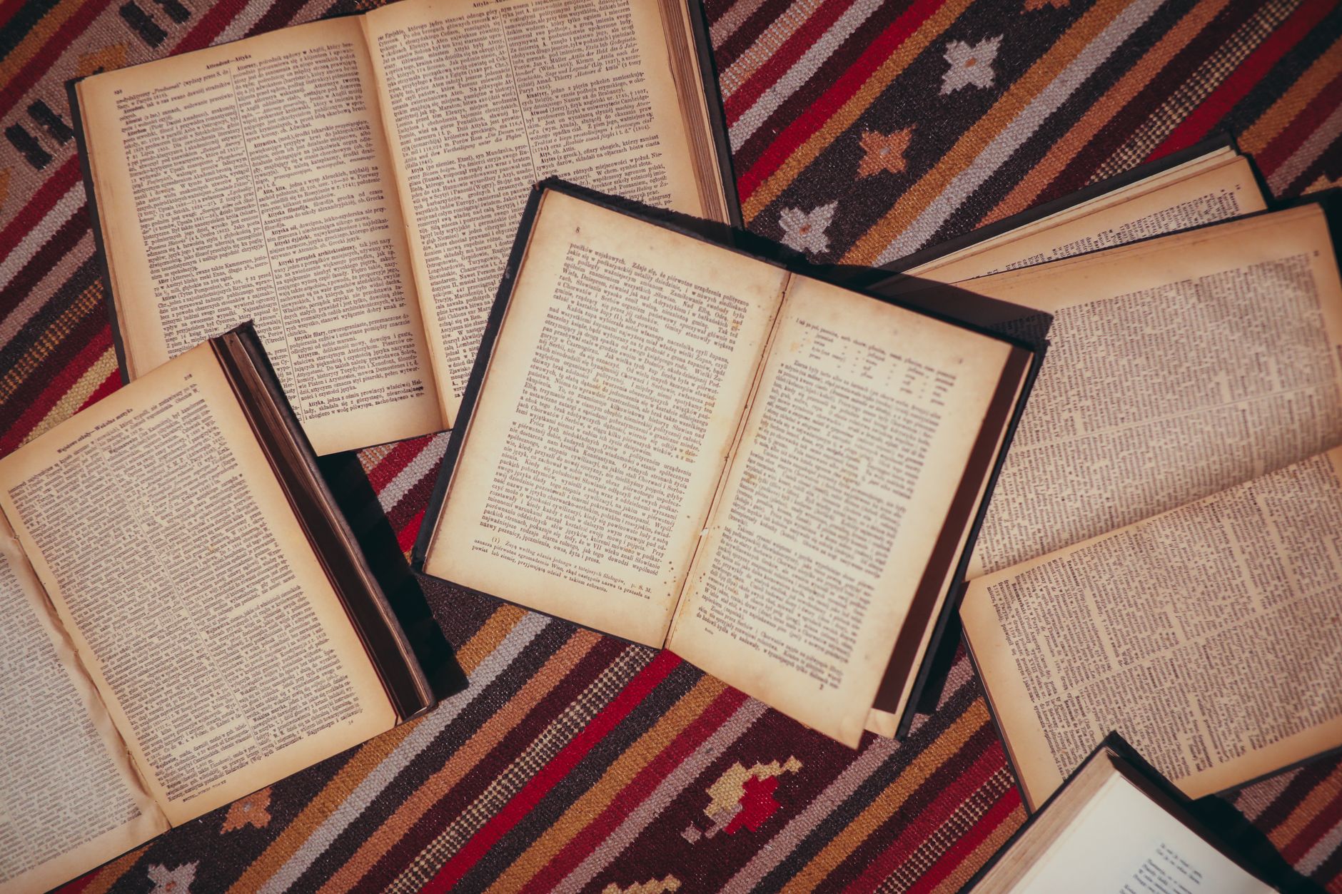 A stack of open books on a wooden table in a quiet library setting