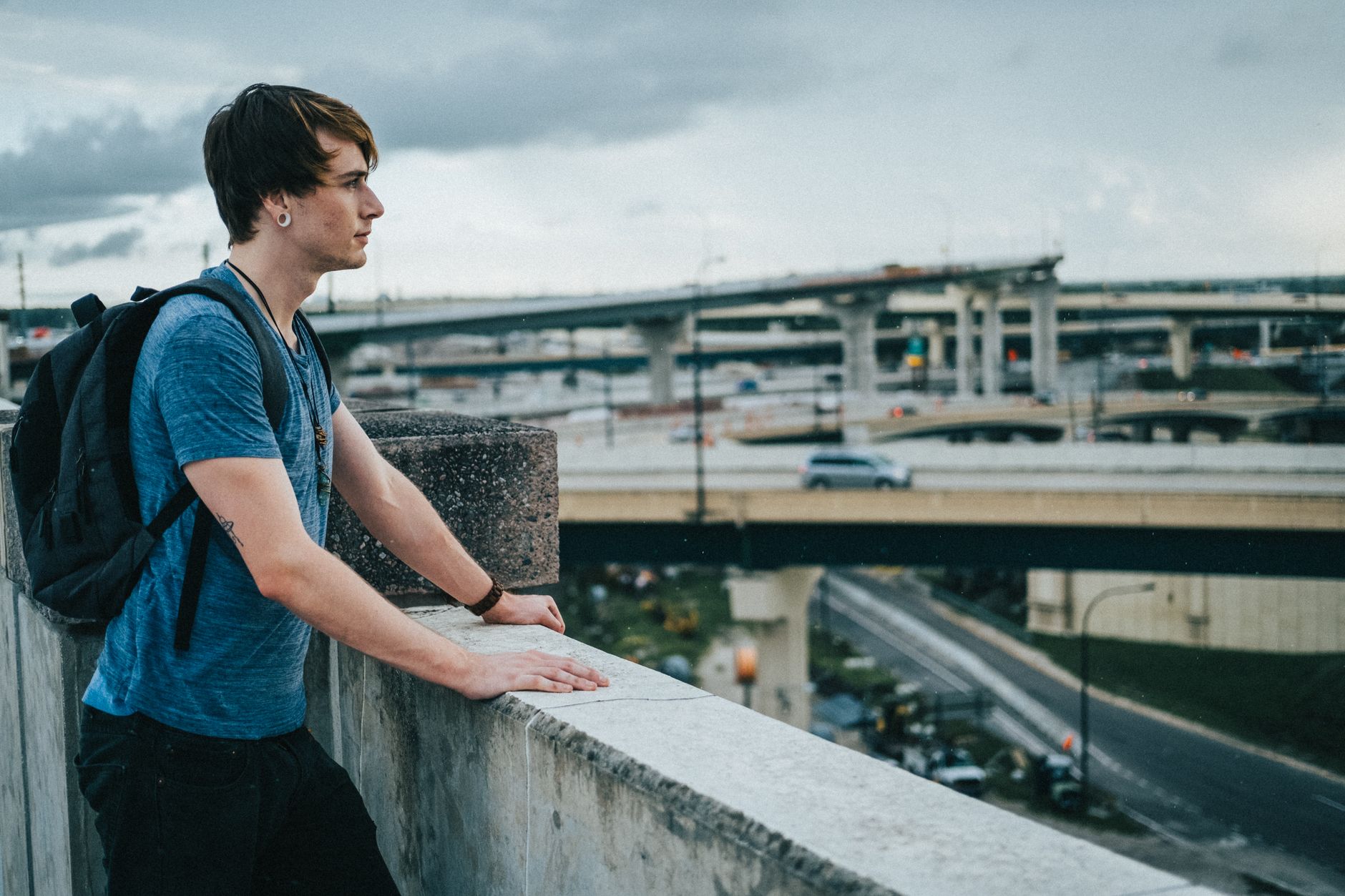 A solitary figure near a highway at dusk, suggesting departure or finality