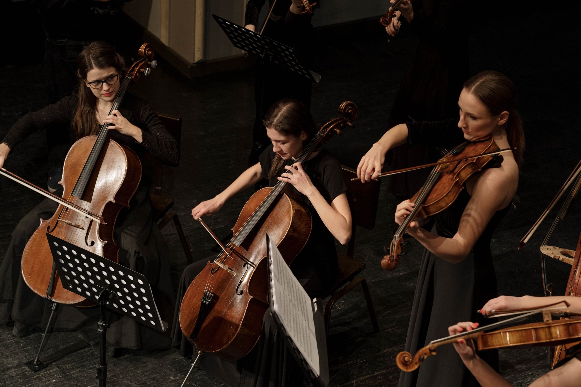 A full orchestra performing on stage under warm stage lighting