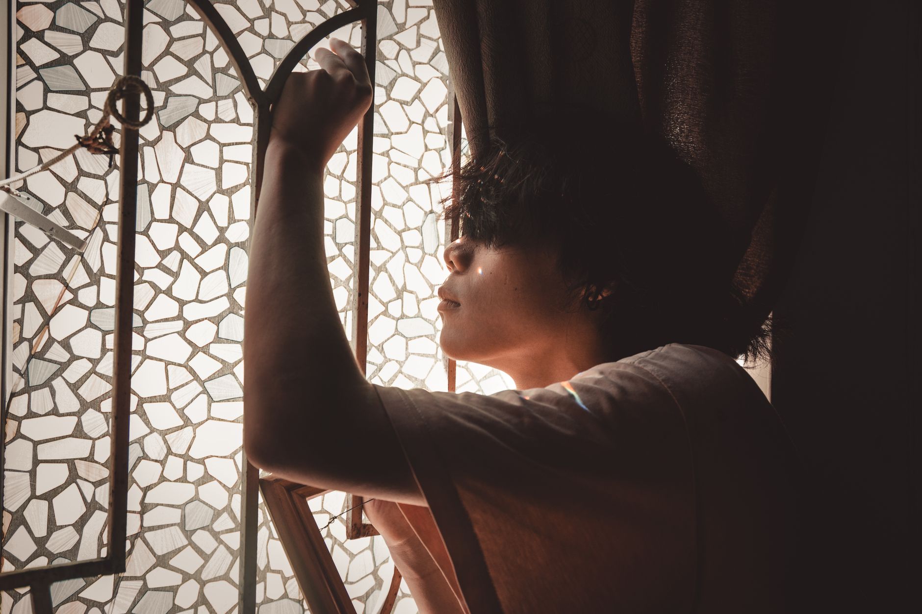 A lone figure silhouetted against a bright window suggesting observation and unknowability