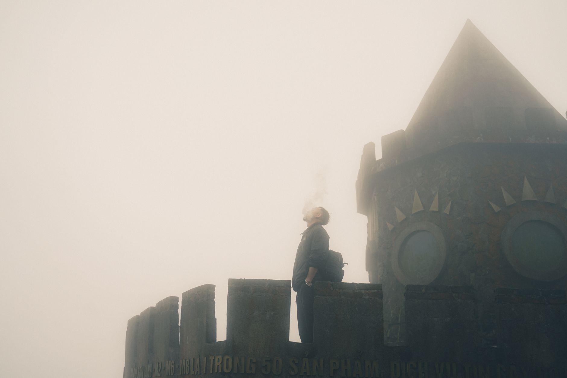 A misty gothic stone building surrounded by fog and dark trees