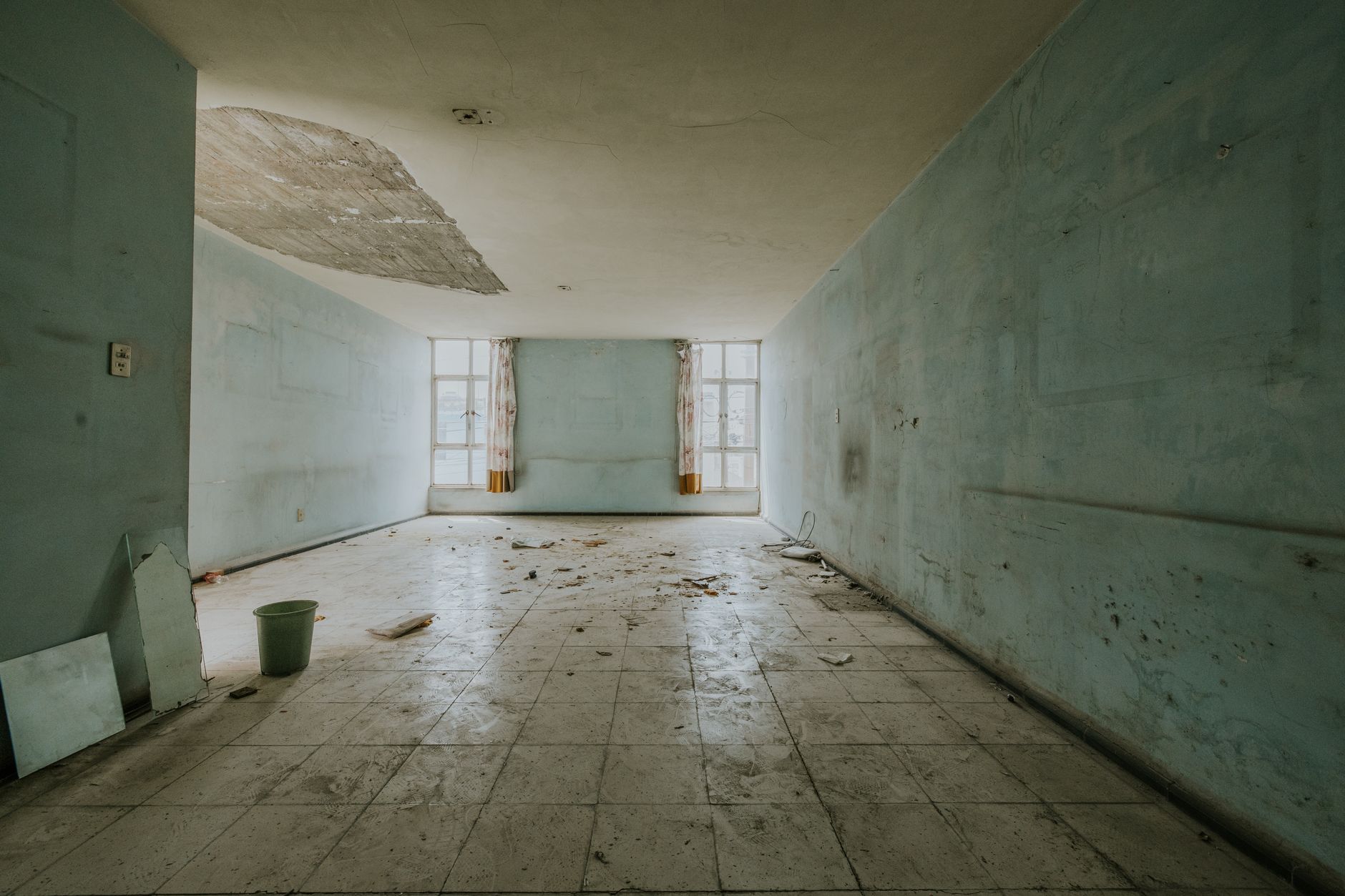 A dimly lit, lived-in room with aging furniture and fading natural light