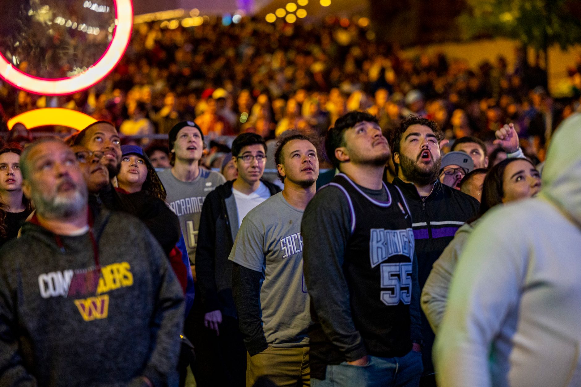 Group of young people waiting in line outside a large entertainment venue at night