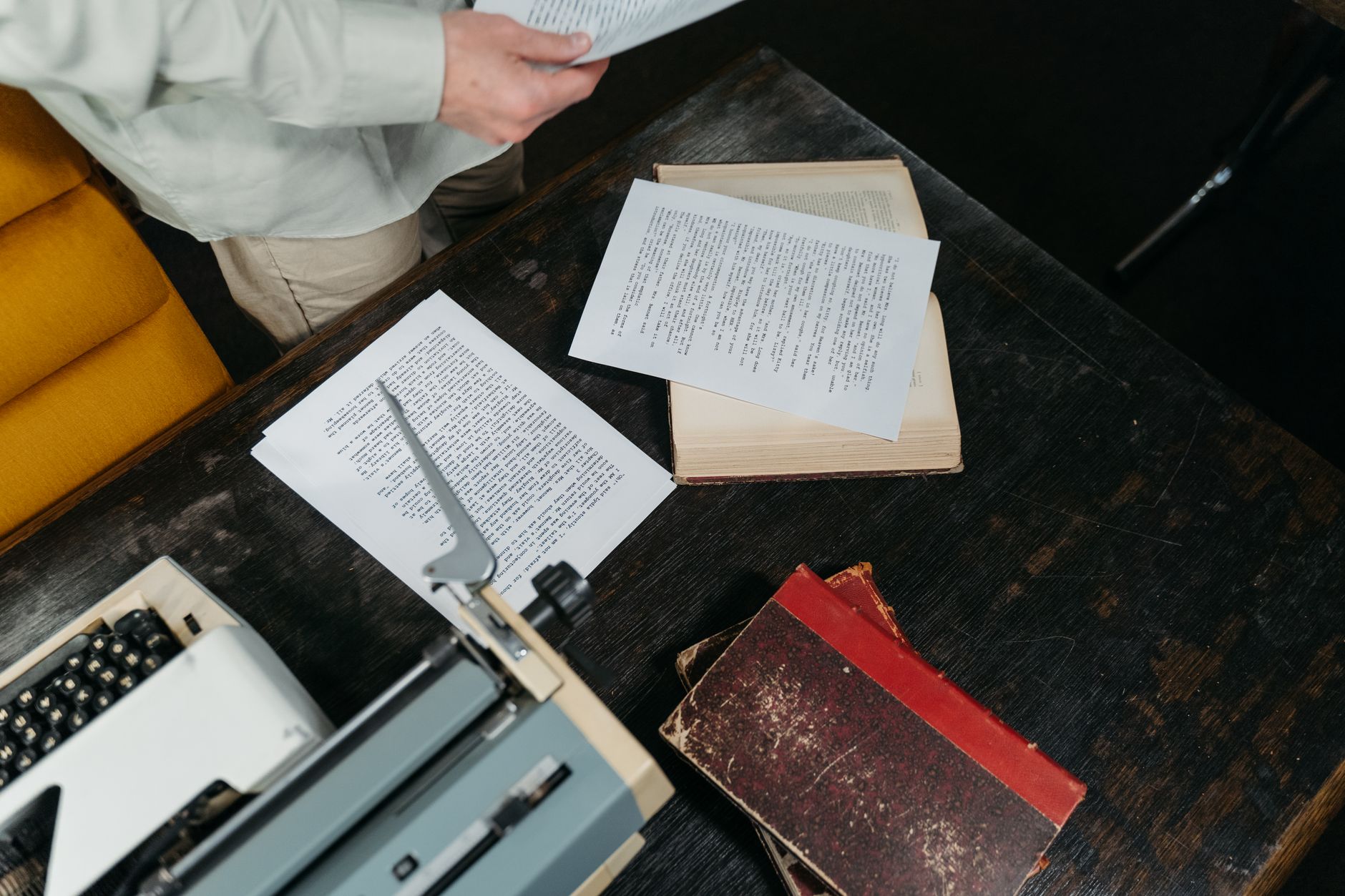 Vintage typewriter on a wooden desk with scattered manuscript pages