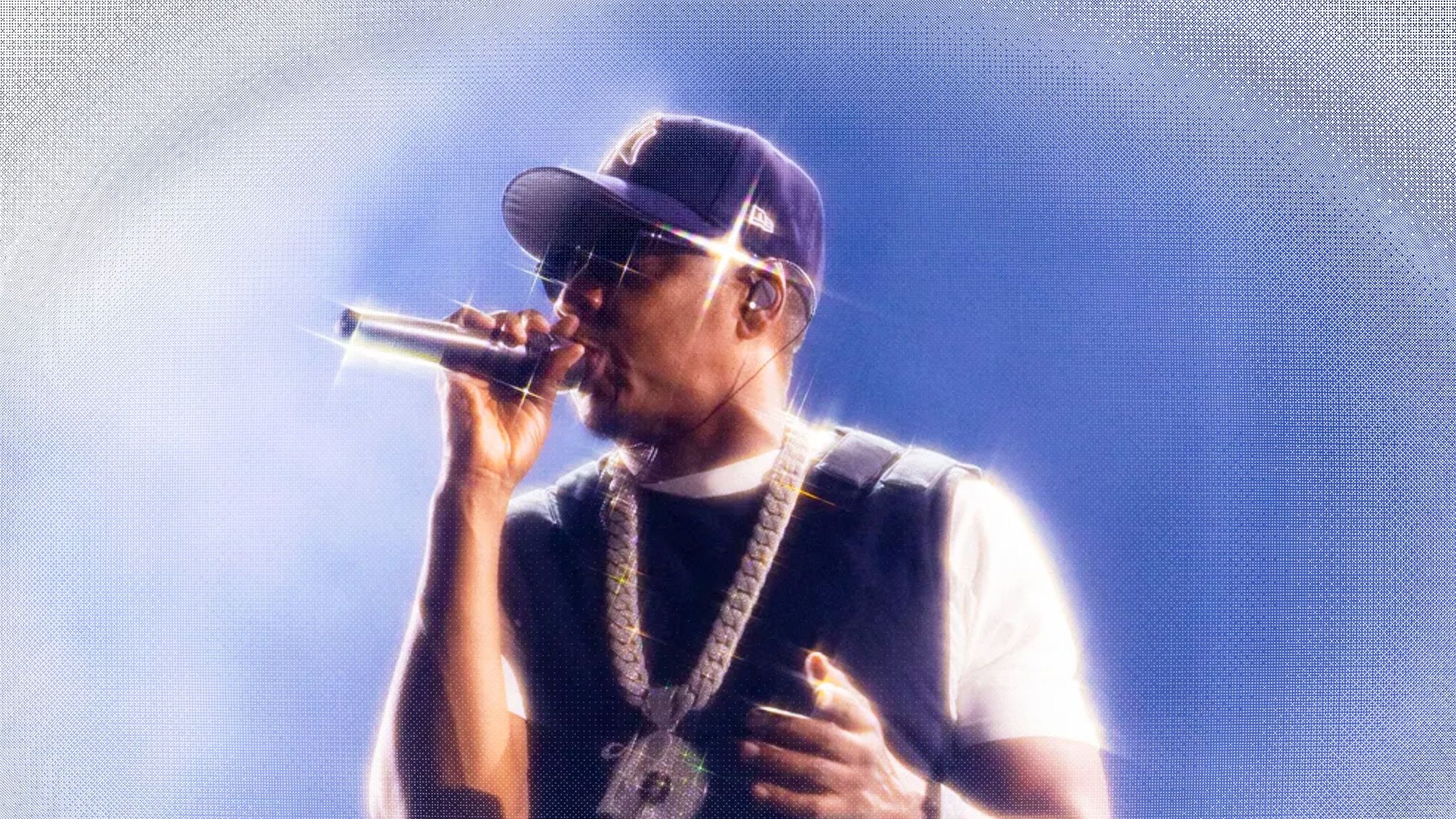 Hip hop artist performing on stage holding a microphone in front of a large crowd